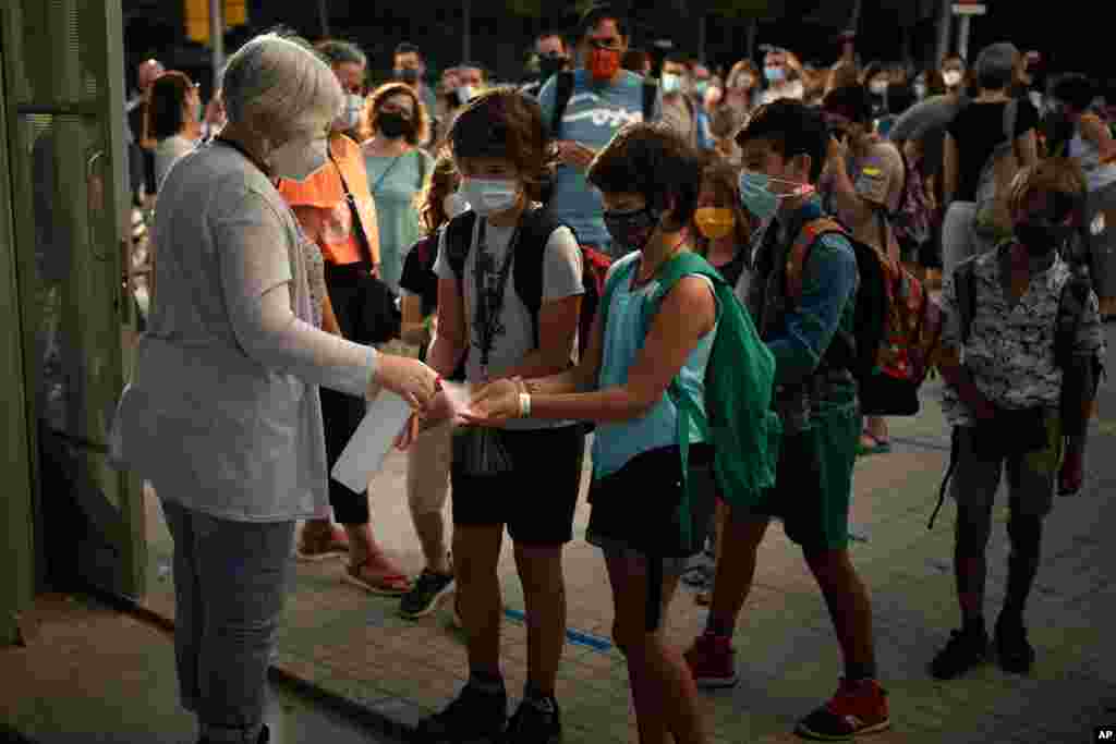 Students wearing face masks to prevent the spread of coronavirus disinfect their hands before entering their school in Barcelona, Spain.