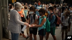 FILE - Students wearing face masks to prevent the spread of coronavirus disinfect their hands before entering their school in Barcelona, Spain, September 14, 2020. 