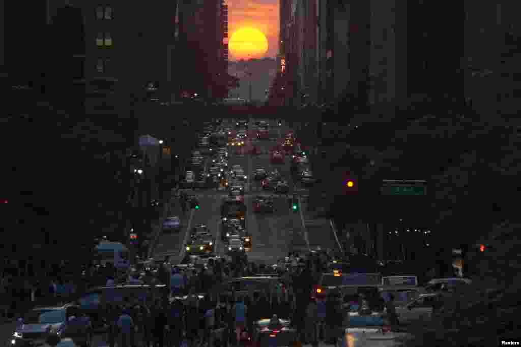 People take pictures of sunset on 42nd street in New York City, during the biannual occurrence named &quot;Manhattanhenge&quot;, May 29, 2013. &quot;Manhattanhenge&quot;, coined by astrophysicist Neil deGrasse Tyson, occurs when the setting sun aligns itself with the east-west grid of streets in Manhattan, allowing the sun to shine down all streets at the same time.