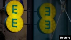 FILE - Signage is seen outside an EE mobile phone shop in Manchester, Britain, Sept, 21, 2017. 