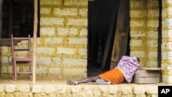 In this Tuesday, Oct. 21, 2014 file photo, a man suffering from the Ebola virus lies on the floor outside a house in Port Loko Community, situated on the outskirts of Freetown, in Sierra Leone. (AP Photo/Michael Duff, File)