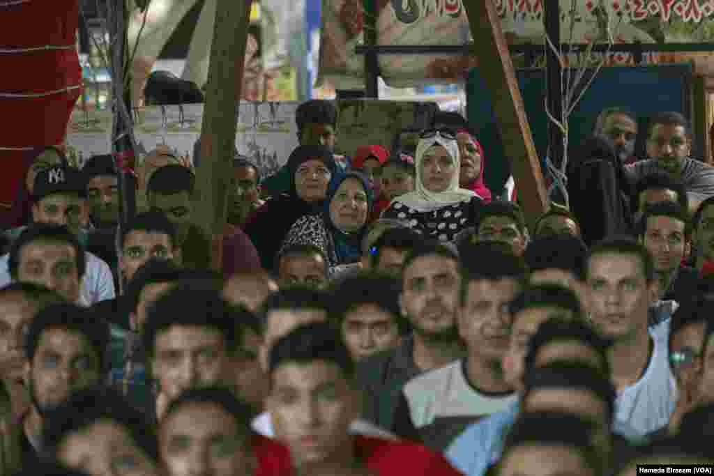 A group of women squeeze in the corner to watch a football game with men in Shubra in Cairo, June 15, 2018.