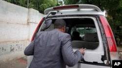 Abdiqadir Dulyar, director for the Somali television station Horn Cable, looks at the smashed window of a car that was carrying journalists working for his station in Mogadishu, May 3, 2016. Unidentified gunmen opened fire on the car last week but no one
was hurt.