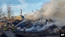 In this photo provided by the Ukrainian Emergency Service, emergency services personnel work to extinguish a fire following a Russian rocket attack in Lviv, Ukraine, Nov. 17, 2024.