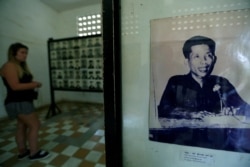 FILE - A visitor walks past a picture of Kaing Guek Eav, alias "Duch", a prison commander for the Khmer Rouge regime, at the Tuol Sleng Genocide Museum in Phnom Penh, Cambodia, June 1, 2016.