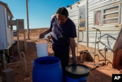 Ricky Gillis collects water for use in a evaporative air cooling unit, Oct. 9, 2024, at his home on the Navajo Nation in Halchita, Utah.