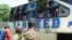 A Kenyan police officer with civilians views a Taheed Bus at the Lamu Police Station in Lamu County, July 19, 2014. 