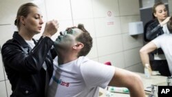 Yulia, wife of Russian opposition figure Alexei Navalny, treats him after unknown attackers doused him with a green chemical solution outside a conference venue in Moscow, Russia, April 27, 2017. 