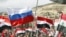 Supporters of Syria's President Bashar al-Assad hold up national flags and a Russian flag as they attend a rally at Umayyad square in Damascus, Syria, March 15, 2012.