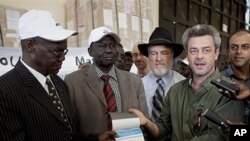 Eamon Omordha, right, Deputy Director of United Nations Integrated Referendum and Electoral Division, hands over a referendum ballot to Justice Chan Reec Madut, left, Chairman of the Southern Sudan Referendum Bureau, during a material handover ceremony in