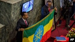 L’ancien Premier ministre Haileamariam Dessalegn, à droite, remet symboliquement le drapeau éthiopien à son successeur Abiye Ahmed, à Addis Abeba, 2 avril 2018.