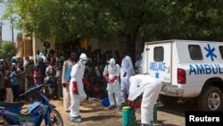 Des agents de santé se revêtant de leurs équipements individuels de protection, afin de désinfecter une mosquée, à Bamako, au Mali, le 14 novembre 2014.