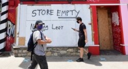 Pedestrians walk past boarded up storefronts on Melrose Avenue in Los Angeles, California, June 1, 2020, following a weekend of looting by people taking advantage of the protest situation in response to the death of George Floyd.