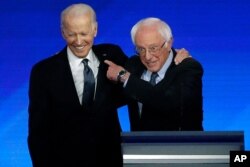 Former Vice President Joe Biden, left, embraces Sen. Bernie Sanders, I-Vt., during a Democratic presidential primary debate, Feb. 7, 2020, hosted by ABC News, Apple News, and WMUR-TV at Saint Anselm College in Manchester, N.H.