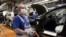 Un empleado se encuentra cerca de vehículos en producción con una máscara facial en la planta de VW en Wolfsburg, Alemania. Volkswagen está lanzando gradualmente la producción en plantas importantes después del cierre de la corona. 