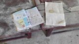 An alphabet book and a notebook lie on top of an elevated wooden floorboard of a middle school in Let Yet Kone village in Tabayin township in the Sagaing region of Myanmar on Sept. 17, 2022, the day after an air strike hit the school. (AP Photo, File)