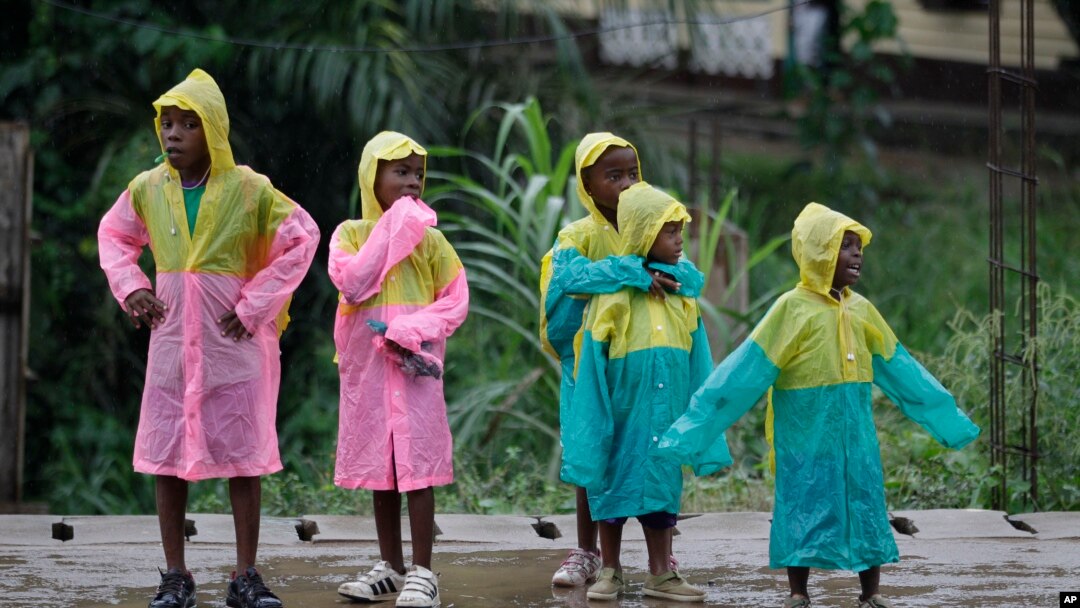 Girls wear matching raincoats as they wait along a roadside during a rain shower in Bata, Equatorial Guinea, (File photo).