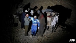 A picture taken Oct. 26, 2017, shows wounded Syrian men standing next to their mules after approaching a meeting point with Israeli soldiers on Mount Hermon in the Israeli-annexed Golan Heights on the border line between Israel and Syria, before being transferred to an Israeli hospital for medical treatment. Israel does not take in refugees from the war in Syria, but its army says that since 2013, it has facilitated the treatment of more than 3,100 wounded Syrians in Israeli hospitals.