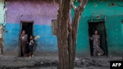 FILE - People stand at the doors of houses that were damaged by shelling in the town of Mehoni, in Southern Tigray, Ethiopia, Dec. 11, 2020. 