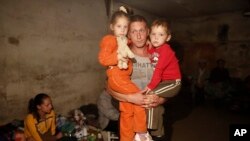 FILE - A local resident holds his children in a basement which is being used as a shelter following shelling in Donetsk, eastern Ukraine.