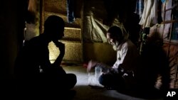 In this photograph taken Aug. 24, 2018, Rohingya spiritual healer Abul Kalam, 60, right, recites verses from the holy Quran in Kutupalong refugee camp, Bangladesh. (AP Photo/Altaf Qadri)