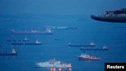 Kapal-kapal labuh jangkar di sekitar di pelabuhan sementara menunggu giliran di berlabuh di terminal pelabuhan dekat Marina Bay Sands, Singapura. (Foto:Dok)