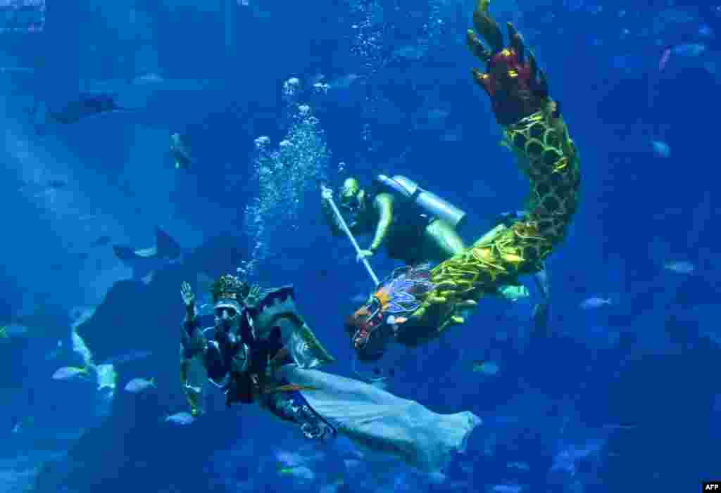 Divers dressed as a sea goddess (L) and a dragon perform underwater during a media preview for Lunar new year celebrations at S.E.A. Aquarium at Resorts World Sentosa in Singapore.