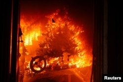 A Christmas tree burns as powerful winds fueling devastating wildfires in the Los Angeles area force people to evacuate, at the Eaton Fire in Altadena, California, Jan. 8, 2025.