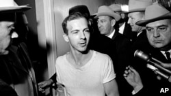 ARCHIVO — Lee Harvey Oswald habla con los medios mientras lo conducen por un pasillo de la estación de policía de Dallas, el 23 de noviembre de 1963, para otra ronda de interrogatorio en relación con el asesinato del presidente estadounidense John F. Kennedy.