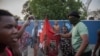 Manifestantes do bairro de Maxaquene preparam-se para queimar uma bandeira do partido Frente de Libertação de Moçambique durante uma manifestação em Maputo, a 24 de outubro de 2024.
