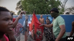 Manifestantes do bairro de Maxaquene preparam-se para queimar uma bandeira do partido Frente de Libertação de Moçambique durante uma manifestação em Maputo, a 24 de outubro de 2024.
