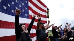 Members of the Proud Boys cheer on stage as they and other right-wing demonstrators rally, Sept. 26, 2020, in Portland, Ore.