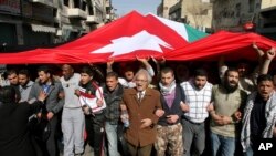 Jordanian supporters of the Islamic Action Front carry a giant Jordanian flag as they demand for political reforms during a protest in Amman, March, 4, 2011.