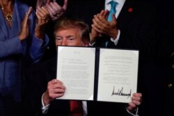 FILE - U.S. President Donald Trump holds an executive order relieving qualified disabled veterans of federally held student loan debt at the AMVETS (American Veterans) National Convention in Louisville, Kentucky, Aug. 21, 2019.