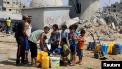 Des enfants collectent de l'eau après cinq jours de trève à Khan Younis dans le sud de la bande de Gaza, le 14 août 2014.