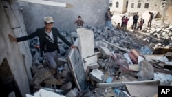People gather near the rubble of houses destroyed by Saudi airstrikes near the airport in Sana'a, Yemen, March 31, 2015. 