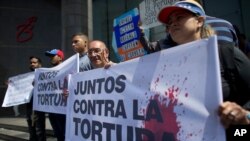 Activistas de la oposición sostienen una pancarta que dice en español "Juntos contra la tortura" durante una protesta frente a la oficina del Programa de las Naciones Unidas para el Desarrollo en Caracas, el lunes 15 de julio de 2019.