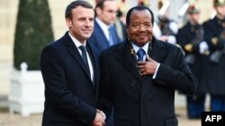 Le président français Emmanuel Macron, à gauche, salue son homologue camerounais Paul Biya à son arrivée à l'Elysée à Paris, le 12 décembre 2017.