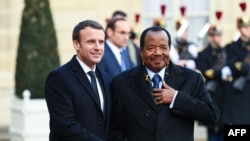 Le président français Emmanuel Macron, à gauche, salue son homologue camerounais Paul Biya à son arrivée à l'Elysée à Paris, le 12 décembre 2017.