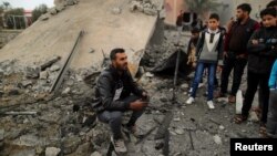  A Palestinian man sits on the remains of a building that was destroyed by an Israeli air strike, in Khan Younis in the southern Gaza Strip, Nov. 12, 2018. Hamas says the airstrikes are related to a failed mission to wiretap its communications.