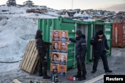 Petugas mempersiapkan spanduk kampanye pemilu di luar tempat pemungutan suara pada hari pelaksanaan pemilihan umum di Nuuk, Greenland, 11 Maret 2025. (Marko Djurica/REUTERS)