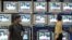 Indian salesman tunes televisions at an electronics shop as government official on screen pledges to boost spending for rural infrastructure, 2006 (file photo).