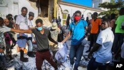 15일 아이티 카이의 지진 피해지역에서 주민들이 수습한 희생자 시신을 운구하고 있다.