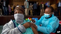 FILE - A woman receives her second Pfizer-BioNTech vaccine jab from a healthcare worker during a vaccination drive in Katlehong, east of Johannesburg, South Africa, Oct. 1, 2021 