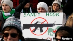 FILE - People hold signs memorializing Sandy Hook Elementary School, where 26 children and adults were killed in a mass shooting in December 2012, as they participate in the March on Washington for Gun Control on the National Mall in Washington, January 26, 2013.