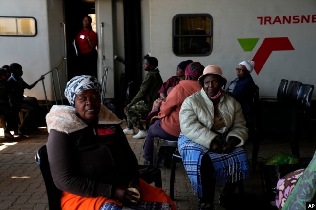 Patients queue for an eye test, outside the Phelophepa eye clinic carriage, in Tembisa, east of Johannesburg, South Africa, Thursday, Aug. 22, 2024. (AP Photo/Themba Hadebe)