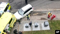 Police detain a man, bottom left laying on the ground, next to a damaged ambulance that he stole after an incident in the center of Oslo, Oct. 22, 2019. 