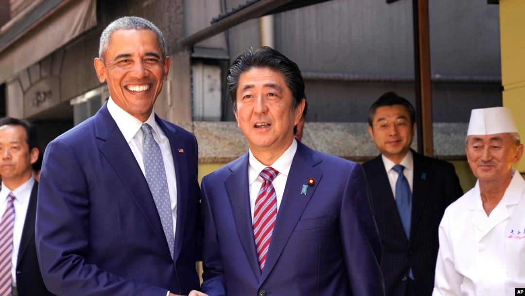 Mantan Presiden AS Barack Obama (kiri) dan Perdana Menteri Jepang Shinzo Abe berpose di depan restoran sushi, Kyubey, di distrik pusat perbelanjaan di Tokyo, 25 Maret 2018. 