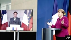 FILE - French President Emmanuel Macron welcomes German Chancellor Angela Merkel in the government building of Toulouse, southwestern France, Oct.16, 2019. 