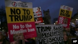 Para pengunjuk rasa memegang poster sambil mendengarkan pidato dalam unjuk rasa di Lapangan Parlemen menentang lawatan Trump ke Inggris, London, 20 Februari 2017.
